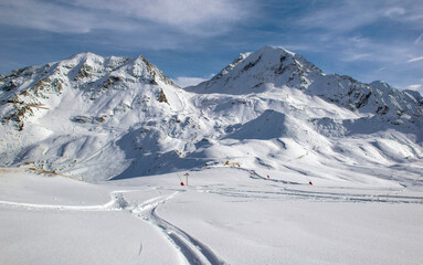 trace of ski touring in the freshly fallen snow on the ski slopes with snowy peak mountain background