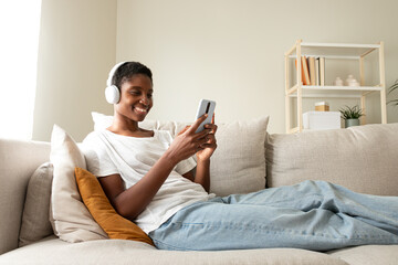 African american woman relaxing on couch listening to music