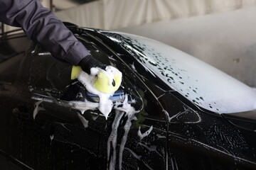 Man washing auto with sponge at car wash, closeup