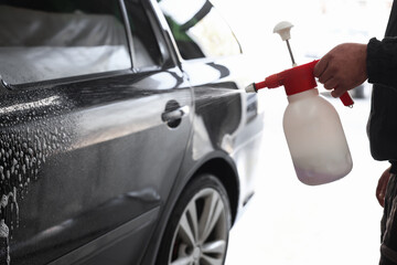 Man washing auto with sprayer at car wash, closeup