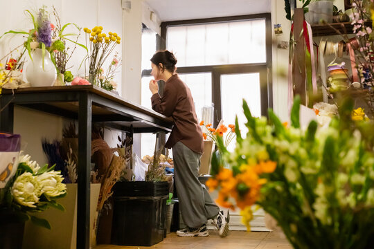 Woman florist works on laptop, accepting orders online in flower shop