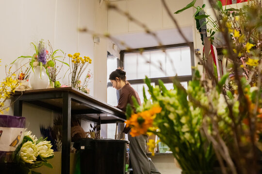 Woman florist works on laptop, accepting orders online in flower shop