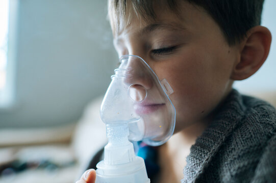 Child using inhaler for cough and cold treatment indoors