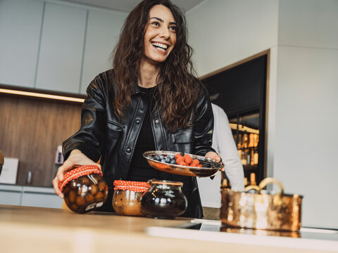 Cooking class participant smiling while preserving fruit in kitchen