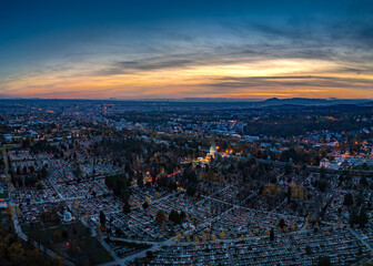 Aerial view of Mirogoj Cemetery's symmetrical rows of gravestones meet the vibrant hues of the Zagreb skyline at dusk, Zagreb, Zagreb, Croatia.