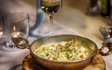 Baked vegetables with cheese sauce and nuts in a brass pan