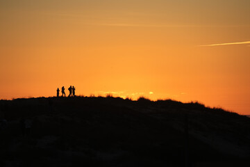 People silhouettes enjoying sunset on coastal dune in Cádiz © Tororio Stock