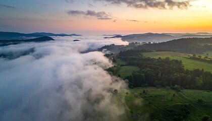 Aerial View of Rolling Hills and Misty Valley During Golden Hour Sunrise With Soft Clouds and Distant Cityscape