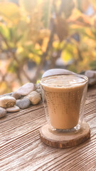 Vertical glass of iced cappuccino coffee drink on wooden table in cafe
