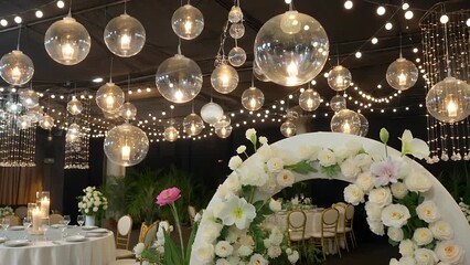 illuminated candle holders suspended above alongside floral displays within a nuptial celebration