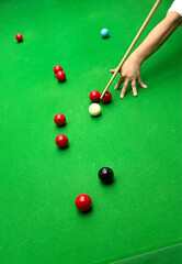 Snooker balls, cue extension stick and green table in indoor room