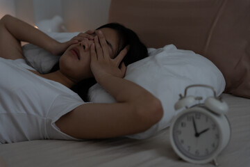 asian woman in bed late trying to sleep suffering insomnia, sleepless or scared in a nightmare, looking sad worried and stressed. Tired and headache or migraine waking up in the middle of the night.