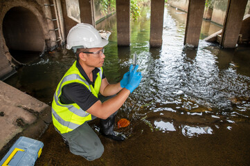 Environmental Scientist Collecting Water Samples Under Bridge alone