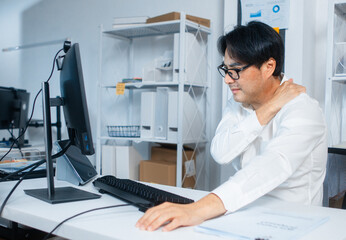 Office syndrome and muscle pain office worker overworking while working on computer sit at desk in office. Tired and stressed Businessman massaging his shoulder feels pain, discomfort, and injury.