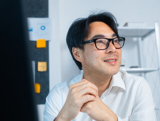 Portrait of Happy Smiling Asian Business manager looking up while sit in office. Professional Asian businessman looking forward to success, goal and achievement. Businessperson portrait.