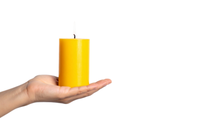 A hand delicately holding a single, unlit yellow candle. The candle stands out with its bright color against the background.