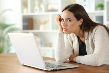 Disappointed woman looks away beside laptop