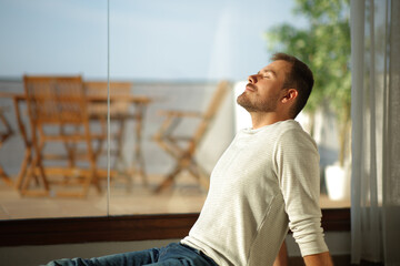Man relaxing breathing fresh air beside a window