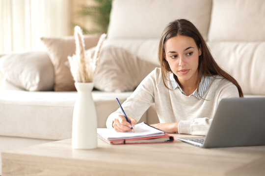 Student taking notes watching online course