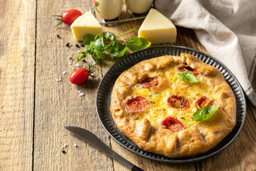 Crispy tomato galette with adyghe cheese and herbs on rustic background.