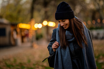 Smiling middle-aged woman wearing scarf and beanie in a park during the autumn season