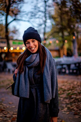 Smiling middle-aged woman wearing scarf and beanie in a park during the autumn season