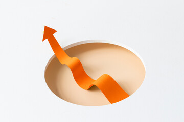 Conceptual success still life image with arrow symbol. One orange arrow symbol breaking out from a circled opening. White background.