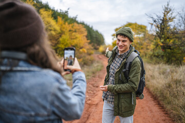Fototapeta premium Woman photographing man with flask during autumn hike