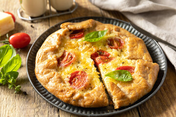 Crispy tomato galette with adyghe cheese and herbs on rustic background.