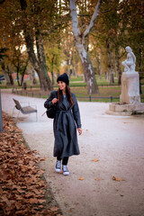 Smiling middle-aged woman wearing scarf and beanie in a park during the autumn season