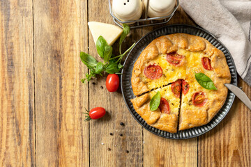 Crispy tomato galette with adyghe cheese and herbs on rustic background. Top view.