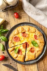 Crispy tomato galette with adyghe cheese and herbs on rustic background. Top view.