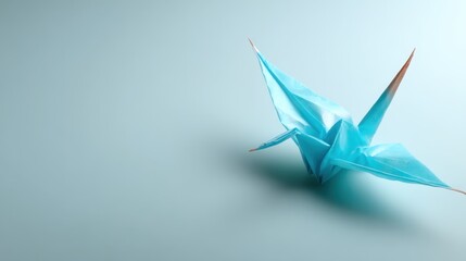 A beautifully crafted blue origami crane poised elegantly on a soft blue surface, symbolizing peace and artistic creativity through its intricate folds.