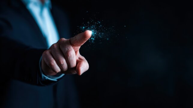 A human hand points towards a glowing cluster of sparkling particles in a dark setting, representing the concept of inspiration, innovation, and the spark of ideas waiting to emerge.