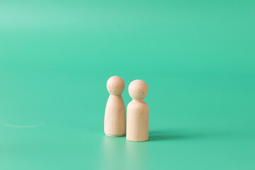 A pair of female and male simple wooden figuring on green background.
