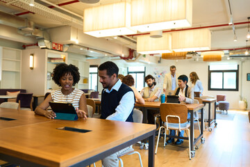Diverse business professionals collaborating using tablet in open office