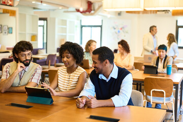 Obraz premium Diverse professionals collaborating using tablet in modern coworking space