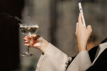 Person holds wine glass and phone during relaxed cafe celebration