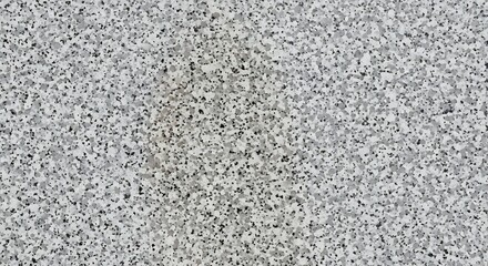 Close up view of a speckled grey and white textured surface with a faint yellow stain