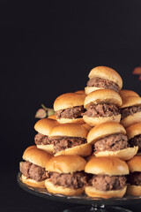 Mini beef sliders stacked on a glass stand with autumn leaves