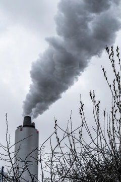 Evening view of industrial chimney emitting vapor under fading light, blending air, environment and climate tones with subtle warming reflection