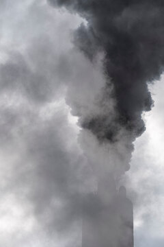 Detail of metallic factory chimney with soft vapor emission against cold air background, depicting warming and environment sensitivity in modern industry