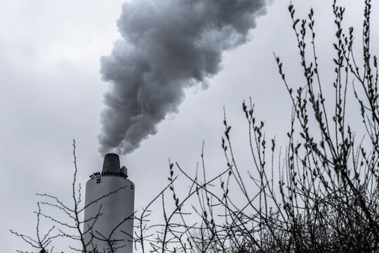Factory chimney rising above misty morning air, vapor softly blending with climate hues, symbol of emission and environment transformation in industry