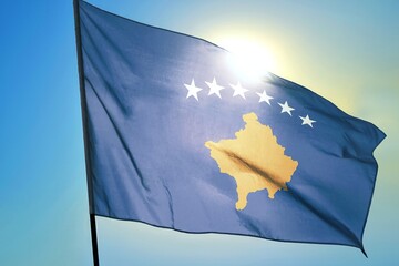 Kosovo national flag waving in sunlight close-up – Republic of Kosovo blue banner with yellow map and six white stars patriotic Balkan country symbol background blue sky bright sunny day