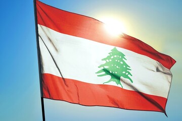 Lebanon national flag waving in sunlight close-up – Lebanese red white red horizontal stripes banner with green cedar tree emblem patriotic Middle East country background blue sky sunny day