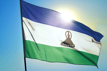 Lesotho national flag waving in sunlight close-up &ndash; Basotho blue white green horizontal stripes banner with black mokorotlo hat emblem patriotic African country background blue sky sunny day