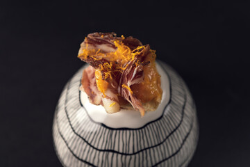 Elegant cured ham canapé with citrus zest on ceramic pedestal