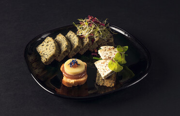 Black plate with assorted gourmet bites and seed bread slices