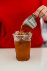A shot of espresso poured into fresh tea in plastic glass