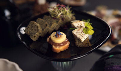 Gourmet plate with artisan bites and seed bread on black pedestal